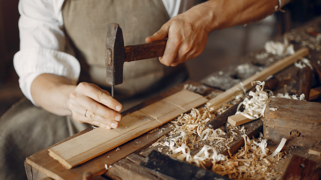 Man working with a wood. Carpenter in a white shirt