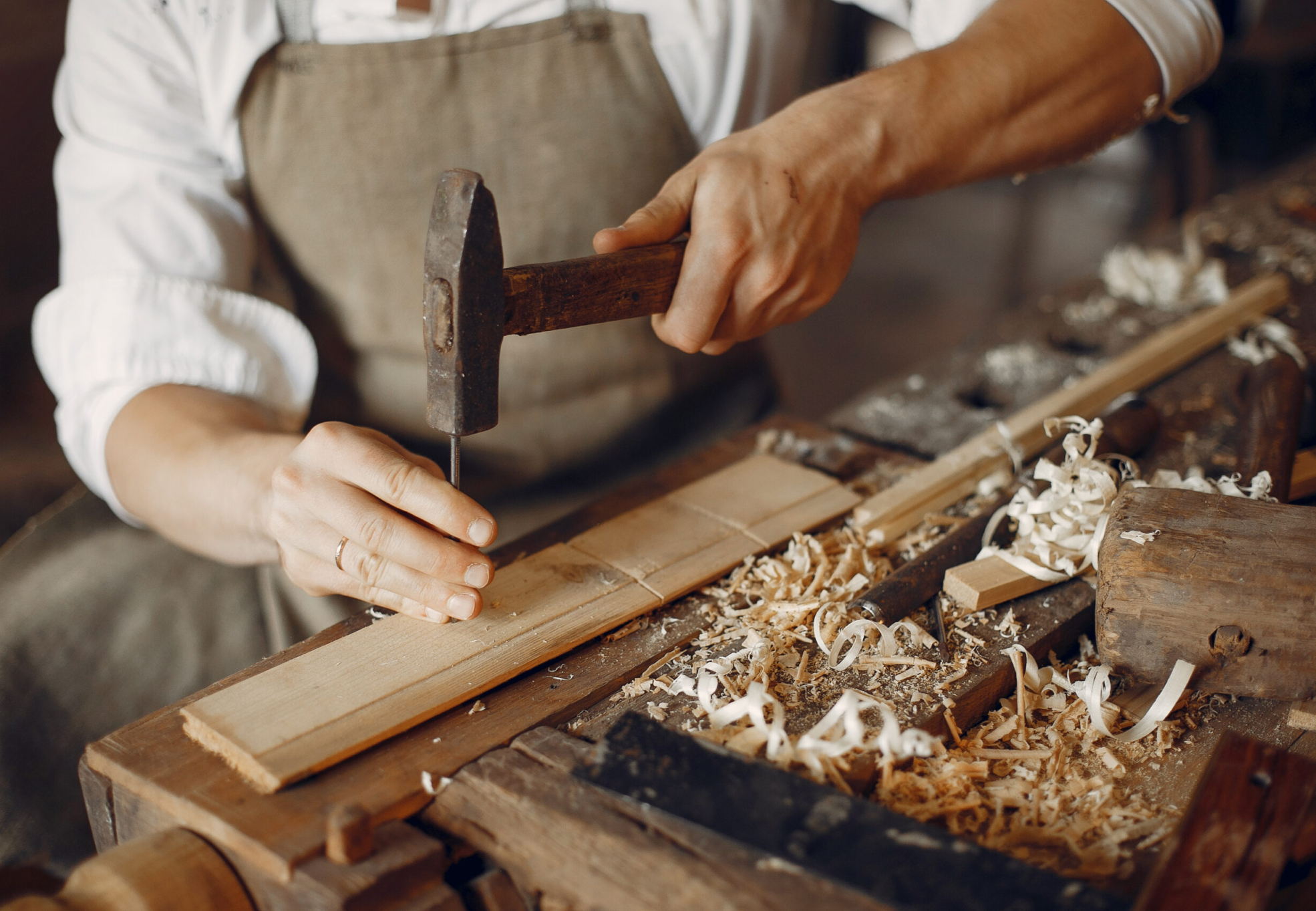Man working with a wood. Carpenter in a white shirt